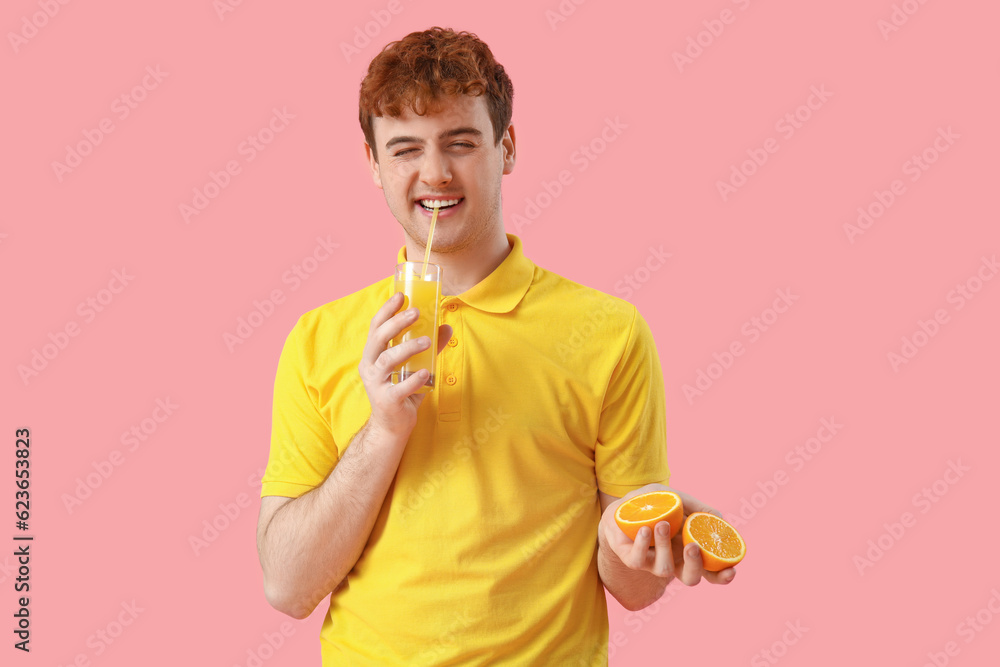 Young man with oranges and glass of juice on pink background