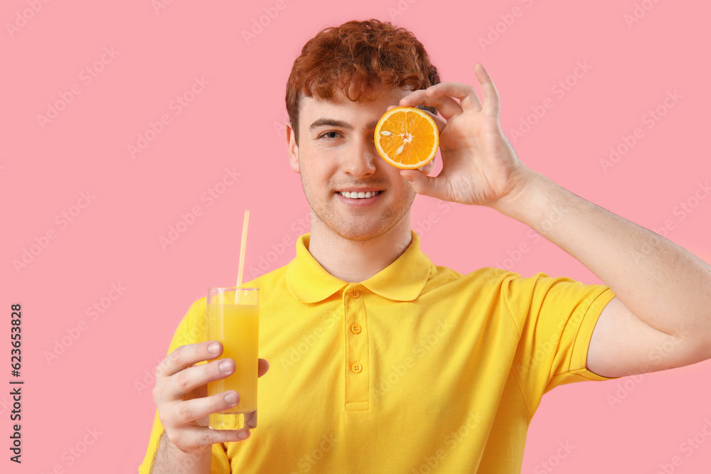 Young man with orange and glass of juice on pink background