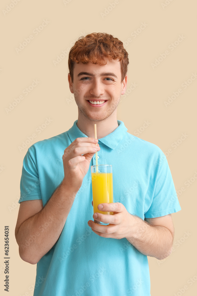 Young man with glass of orange juice on beige background