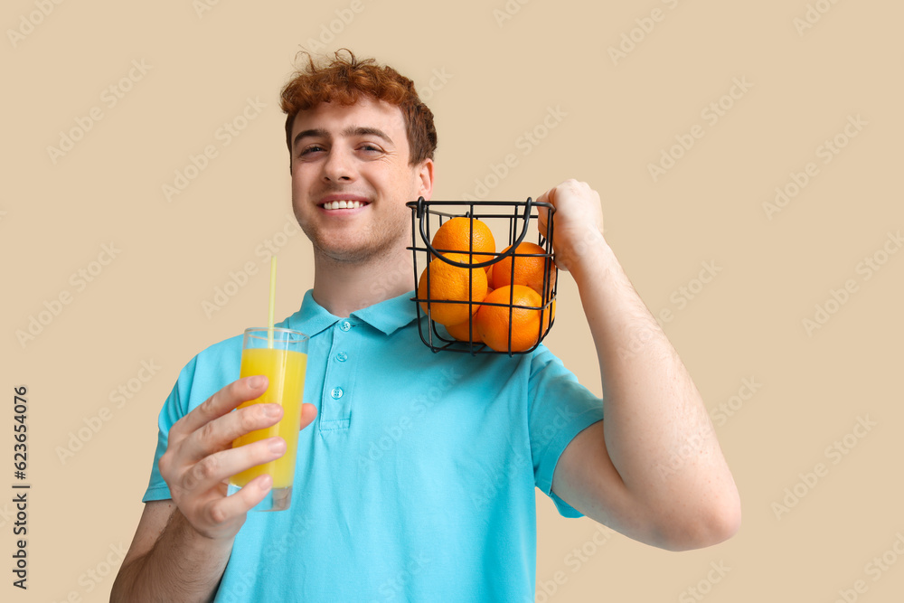 Young man with oranges and glass of juice on beige background