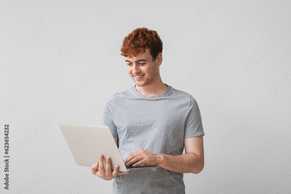 Male programmer working with laptop on light background