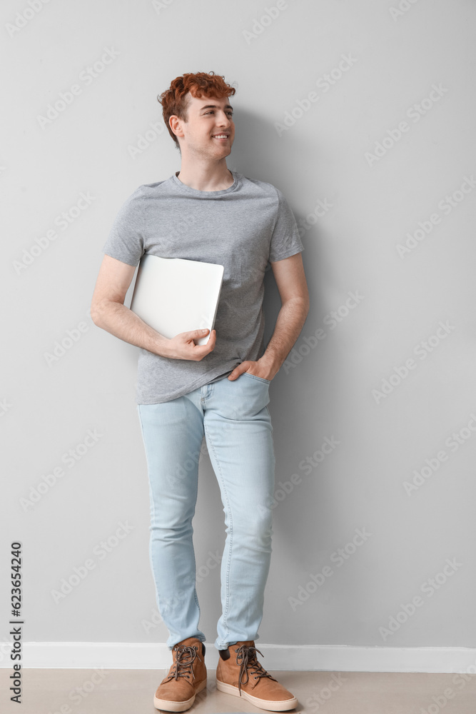 Male programmer with laptop near light wall