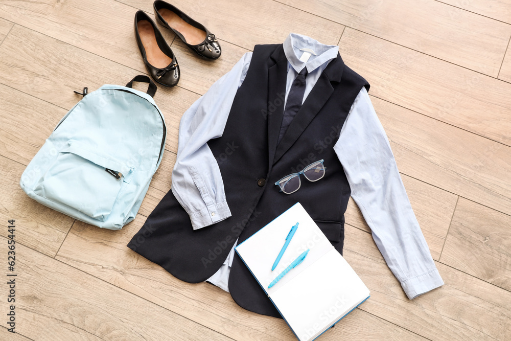 Composition with stylish school uniform, backpack, shoes, notebook and eyeglasses on wooden backgrou