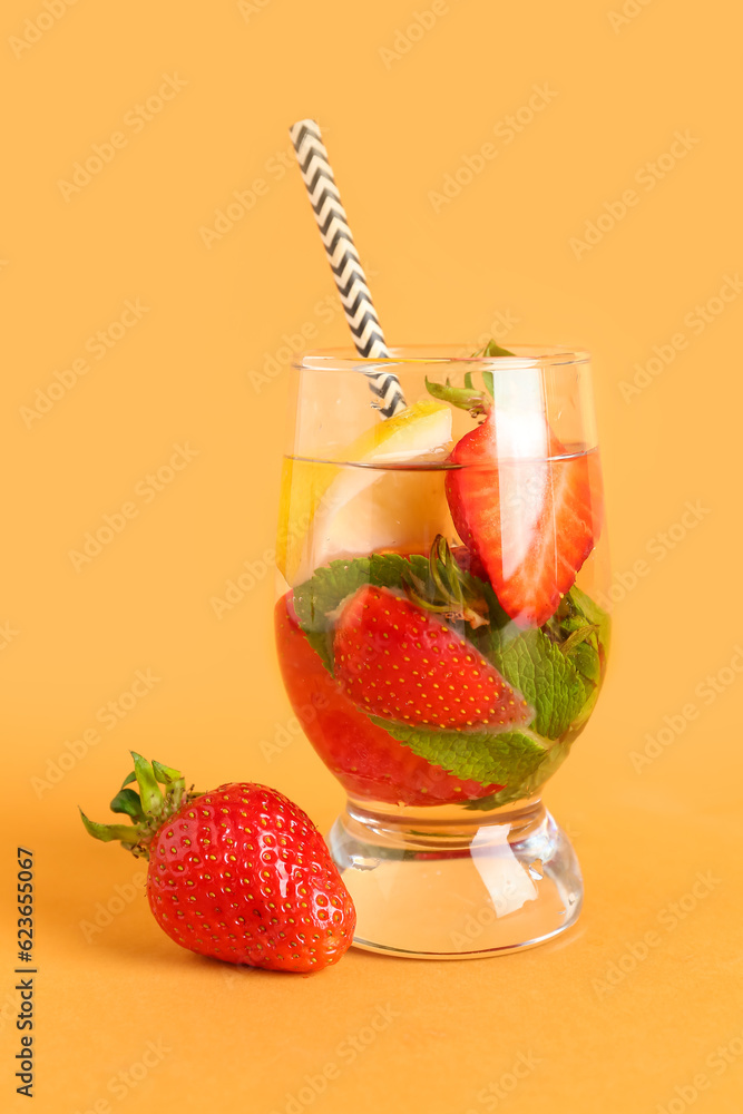 Glass of fresh lemonade with strawberry and lemon on orange background