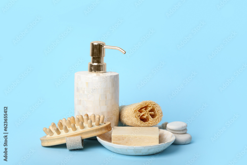 Bottle of cosmetic product, massage brush, soap and bath sponge on color background