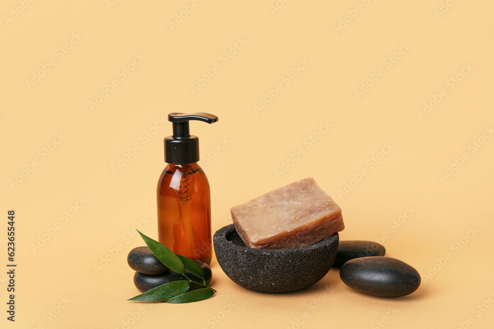 Bottle of cosmetic product, soap bar and spa stones on color background