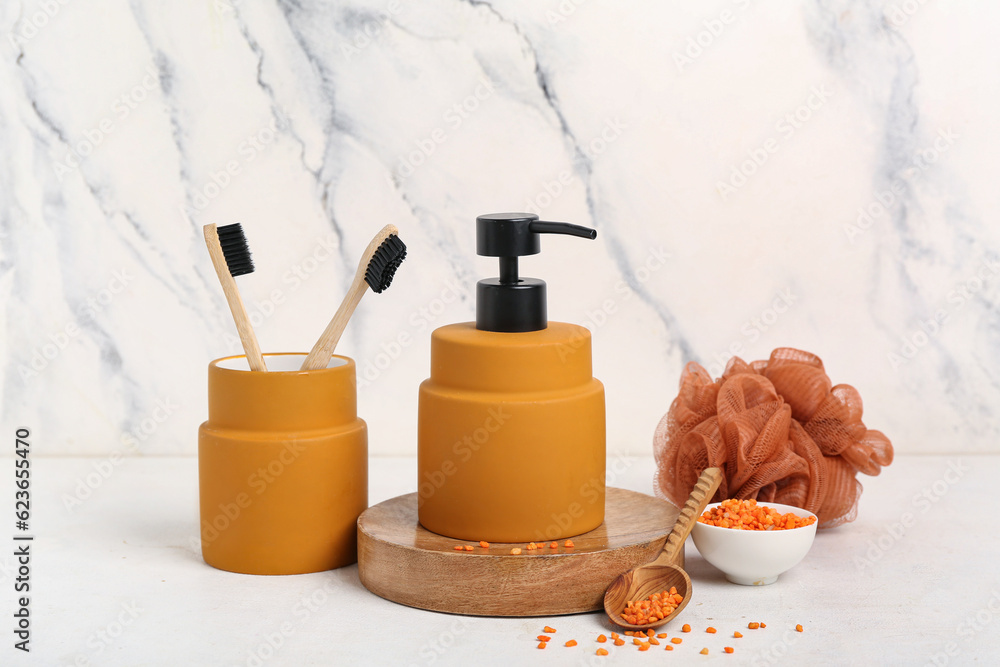 Bottle of cosmetic product, toothbrushes, bath sponge and sea salt on light background