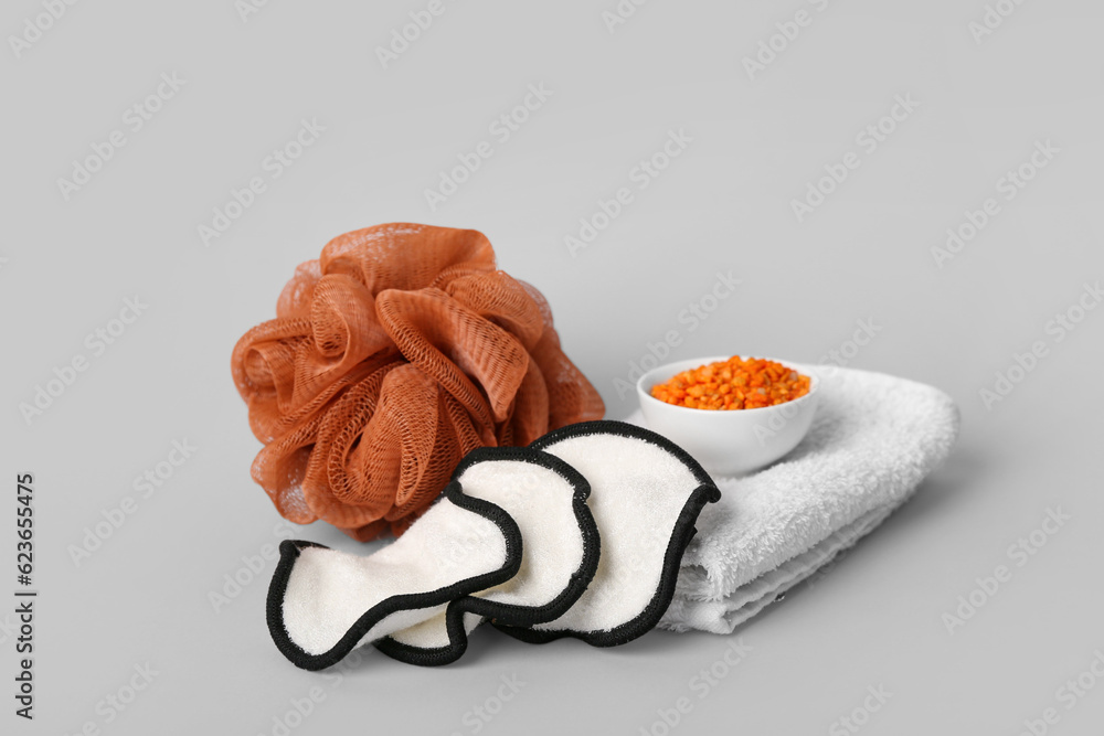 Bath sponge, clean towel, cotton pads and sea salt on grey background