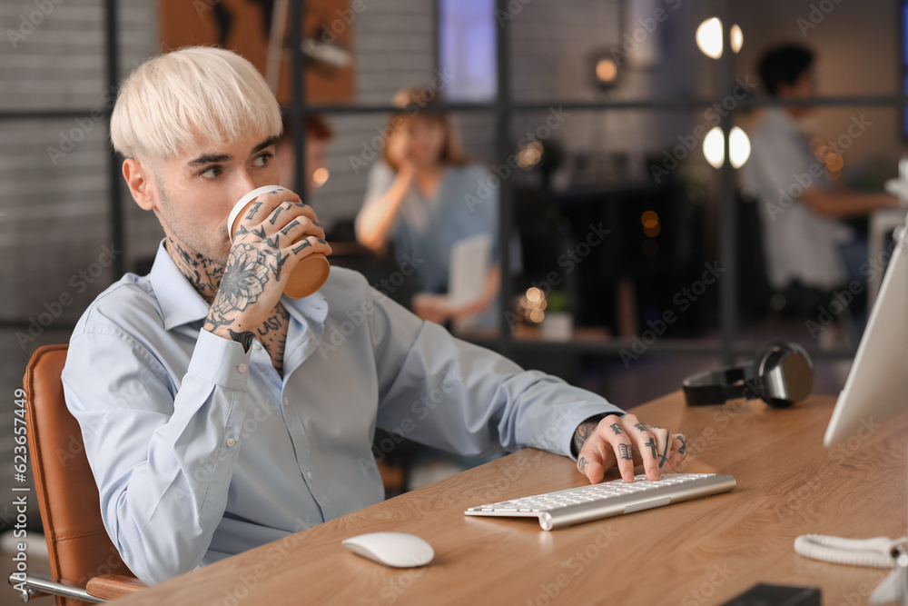 Male programmer drinking coffee in office at night