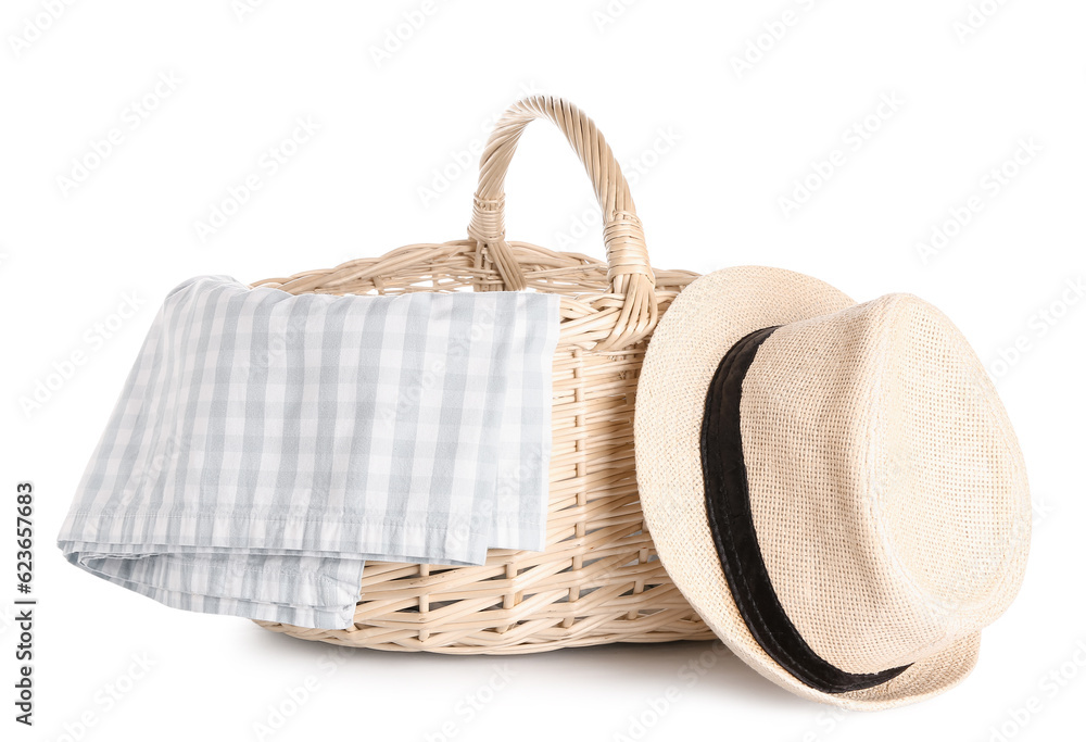 Wicker picnic basket with napkin and hat on white background