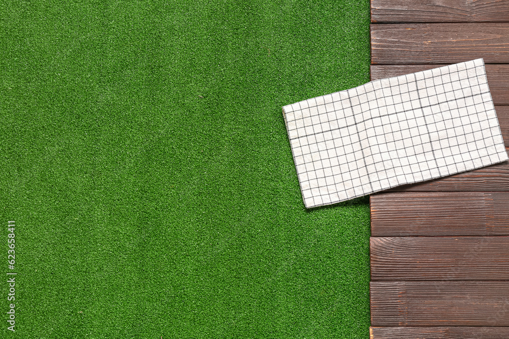 Clean napkin on dark wooden table against green grass background