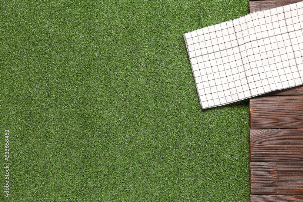 Clean napkin on dark wooden table against green grass background