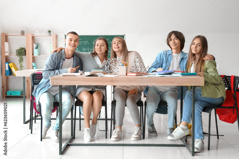 Group of teenage students studying at table in classroom