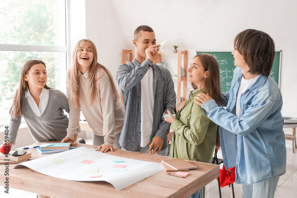 Group of teenage students performing task at table in classroom