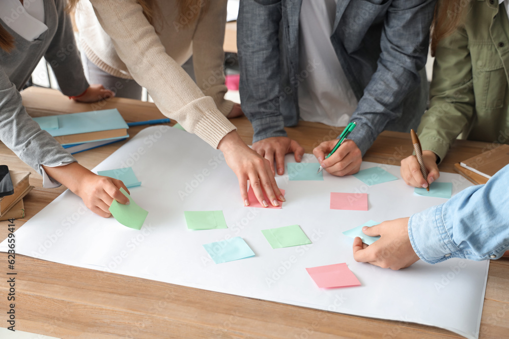 Group of teenage students performing task at table in classroom, closeup