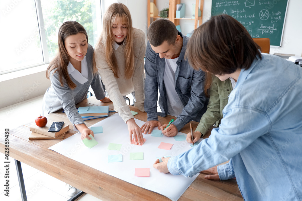 Group of teenage students performing task at table in classroom