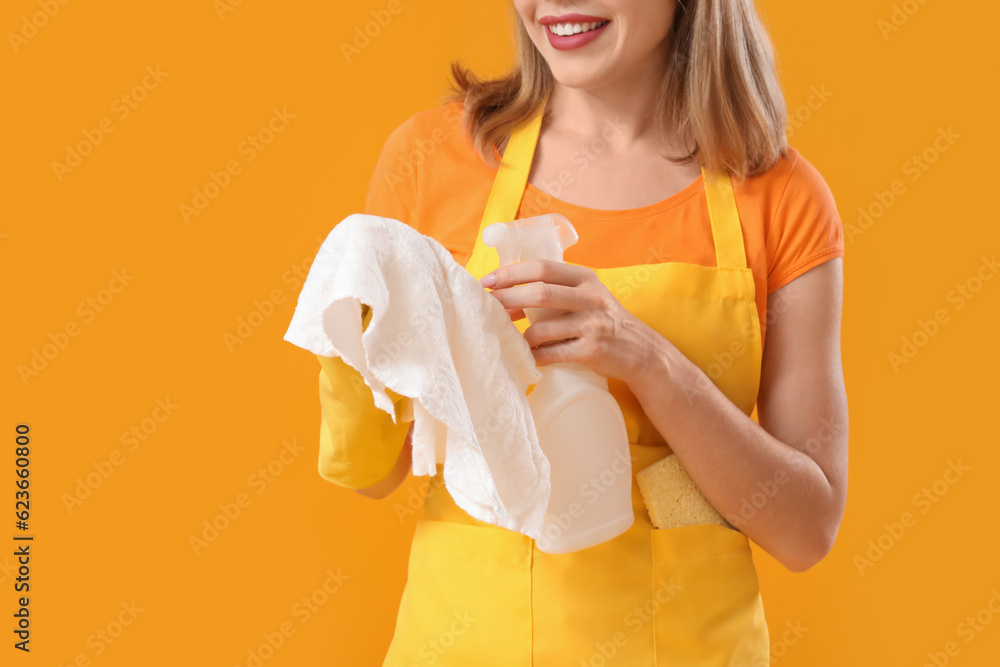 Young woman with bottle of detergent and rag on orange background, closeup