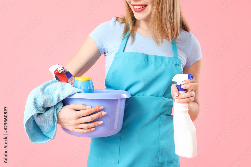 Young woman with cleaning supplies on pink background, closeup