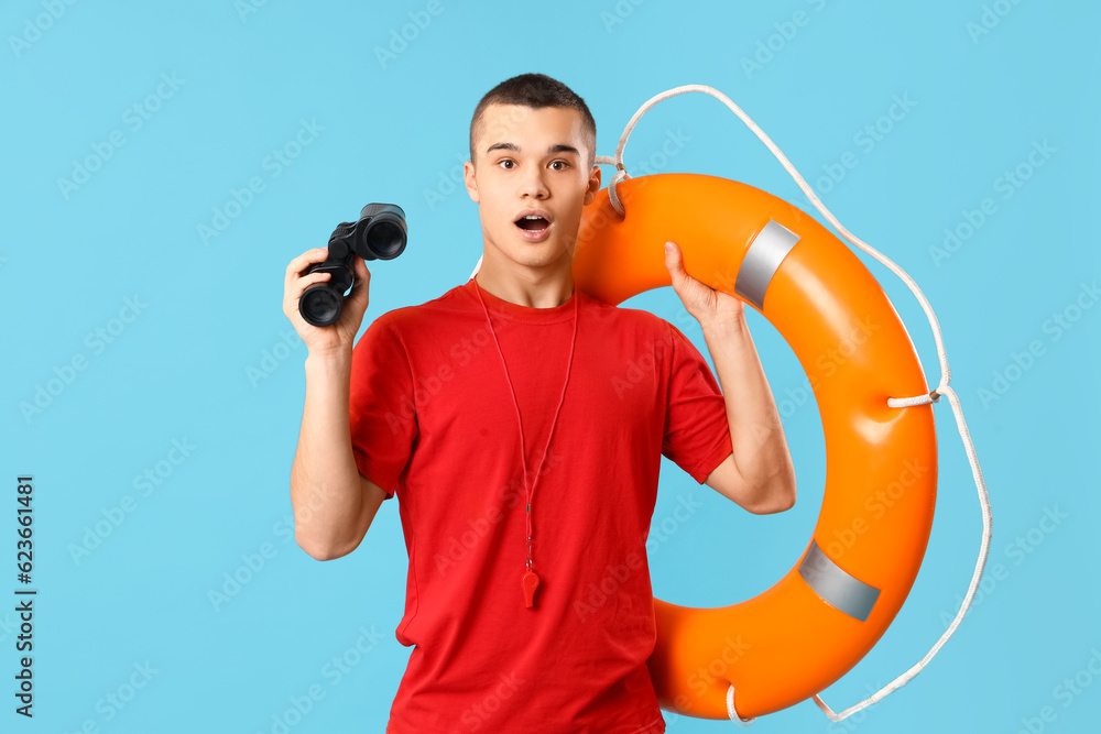 Shocked male lifeguard with binoculars and ring buoy on blue background