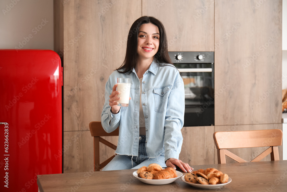 Beautiful woman with glass of milk in kitchen