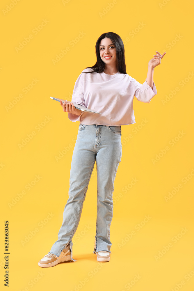 Female programmer with laptop on yellow background