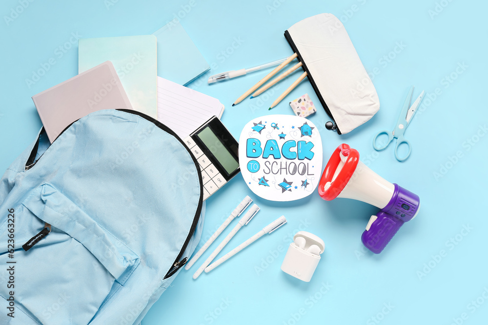 Backpack, stationery, earphones, megaphone and sheet with text BACK TO SCHOOL on blue background