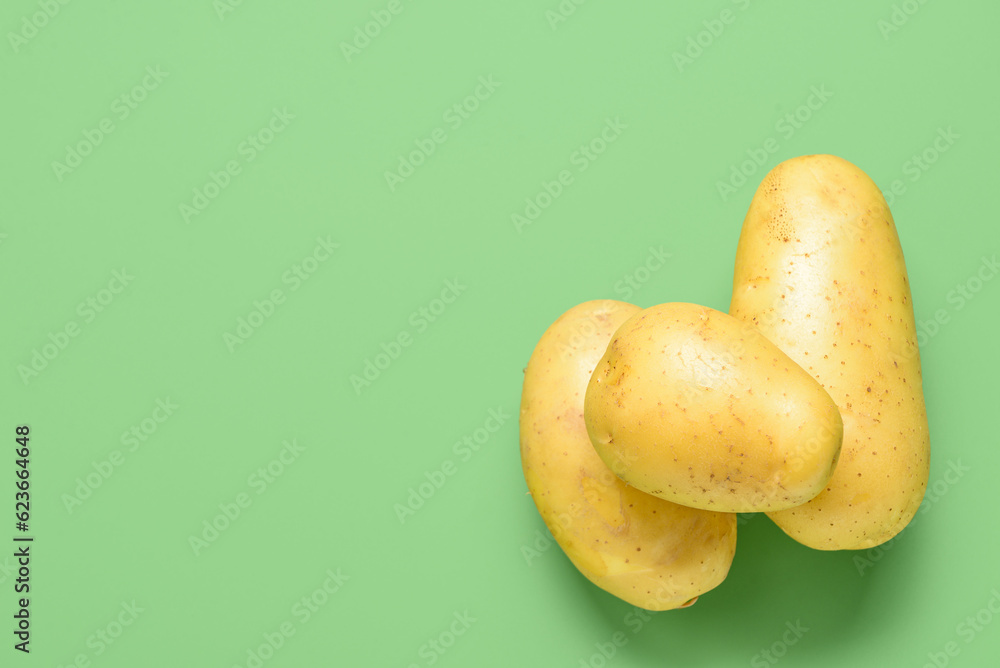 Raw potatoes on green background