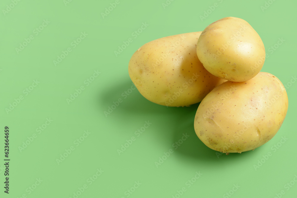 Raw potatoes on green background