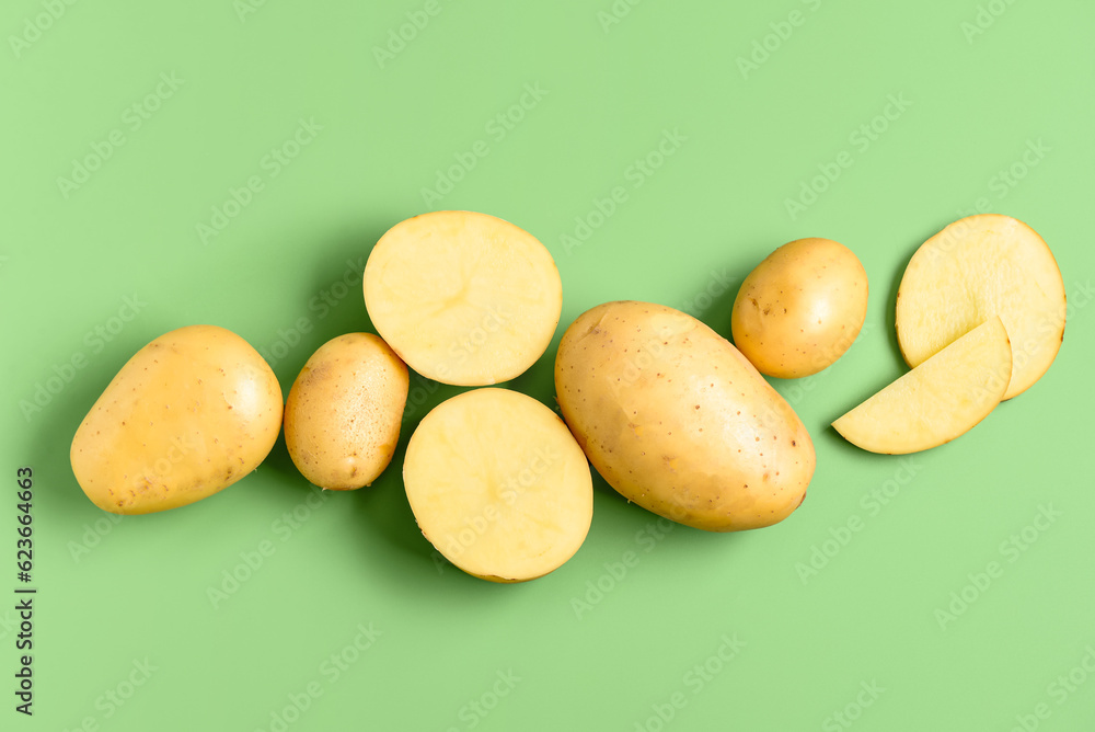 Raw potatoes on green background