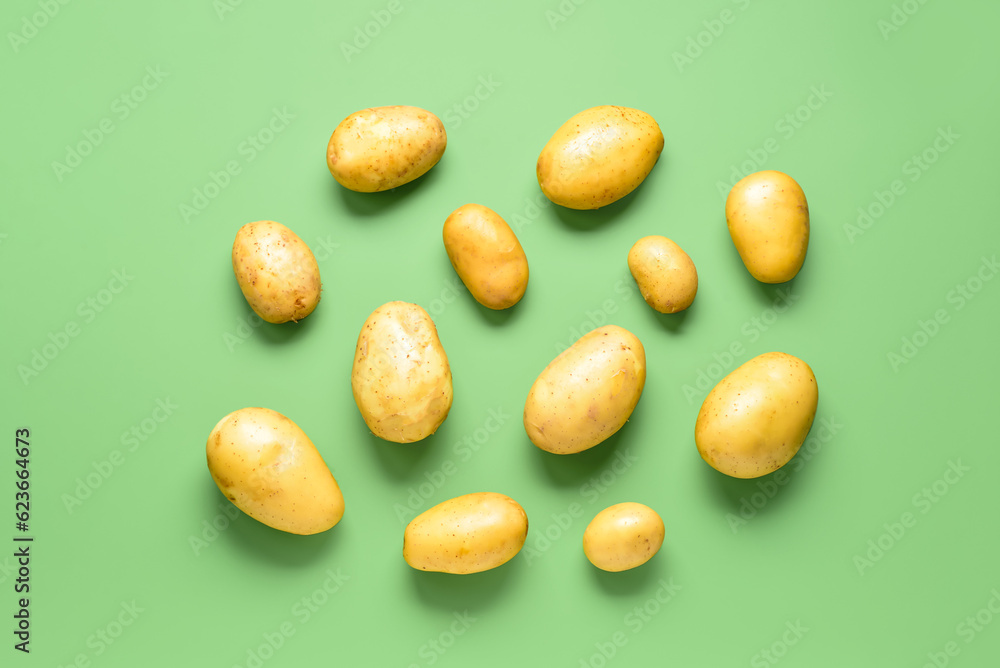 Raw potatoes on green background