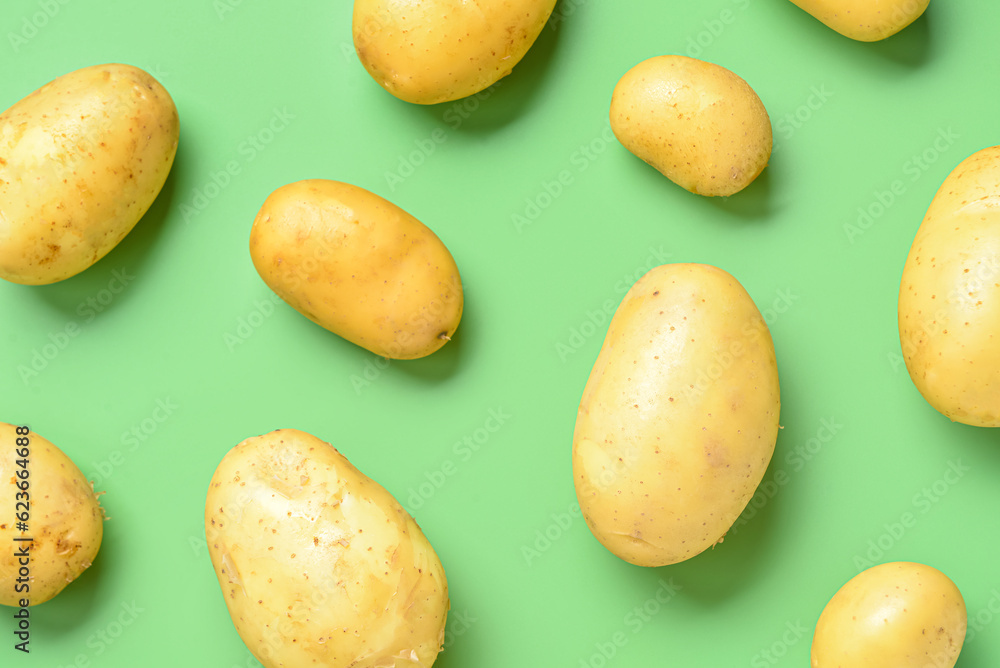 Raw potatoes on green background