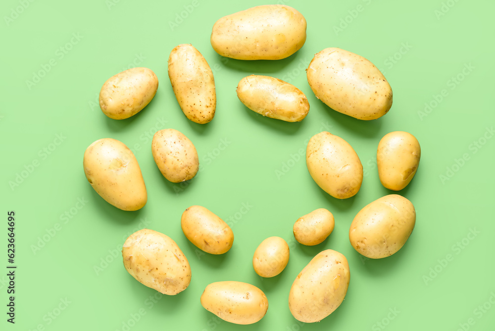 Frame made of raw potatoes on green background