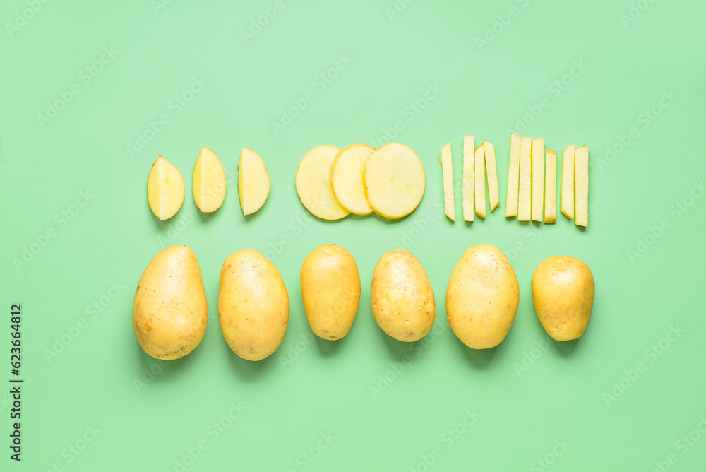 Whole and cut potatoes on green background