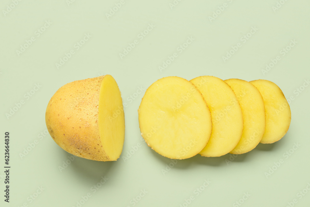 Raw cut potato on green background