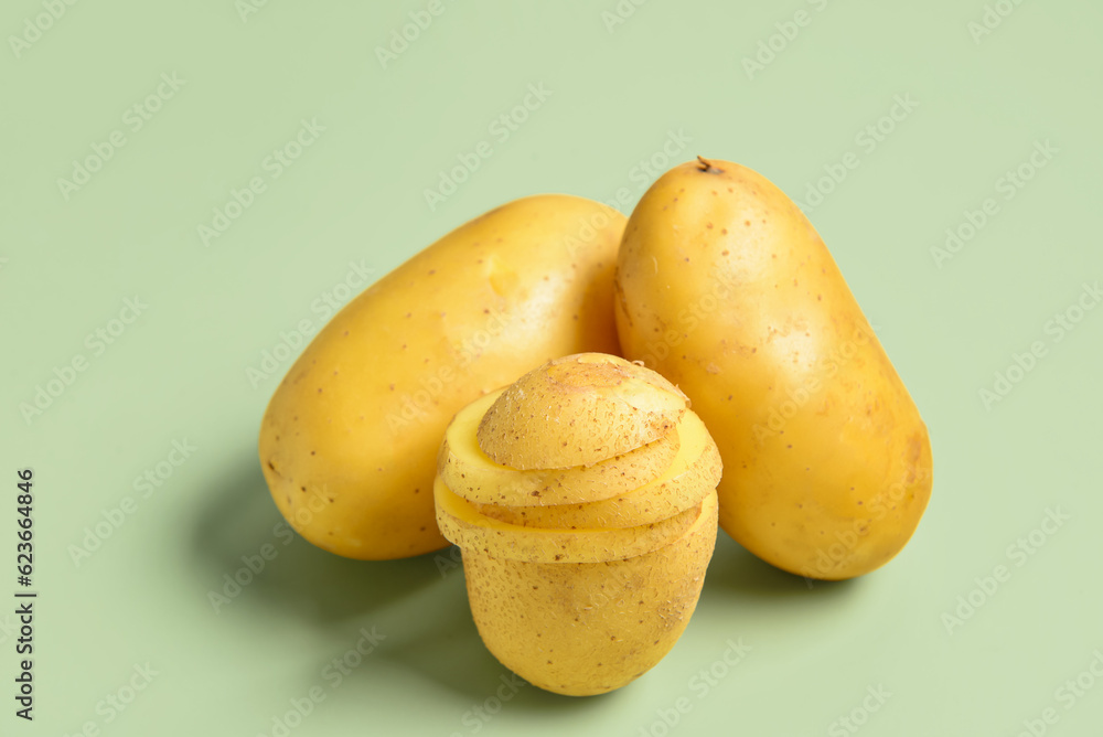 Raw potatoes on green background