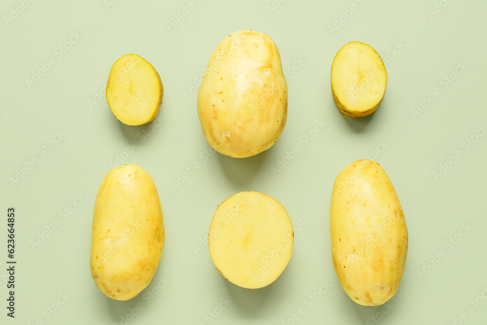 Raw potatoes on green background