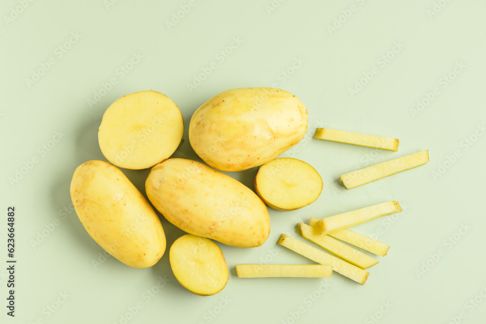 Raw potatoes on green background