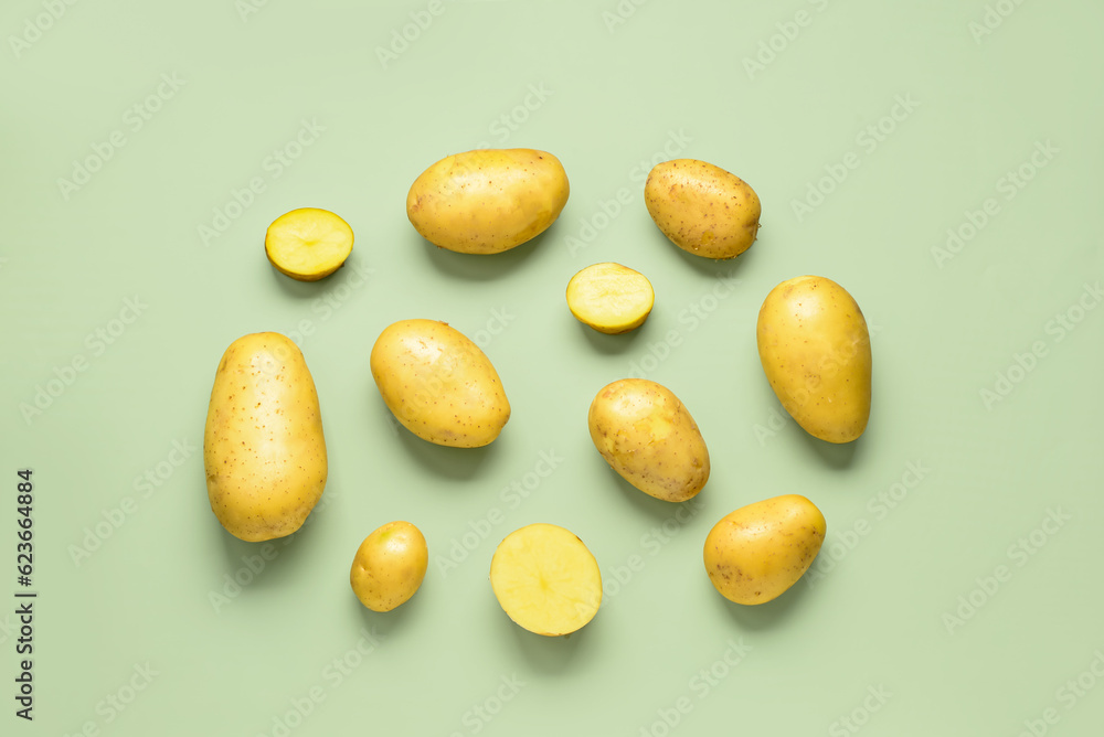 Raw potatoes on green background