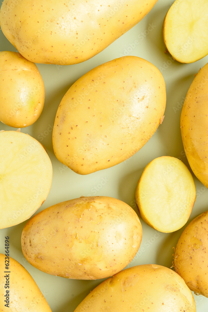 Raw potatoes on green background