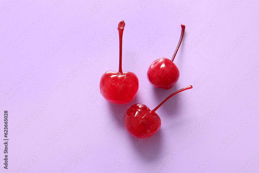 Tasty maraschino cherries on lilac background