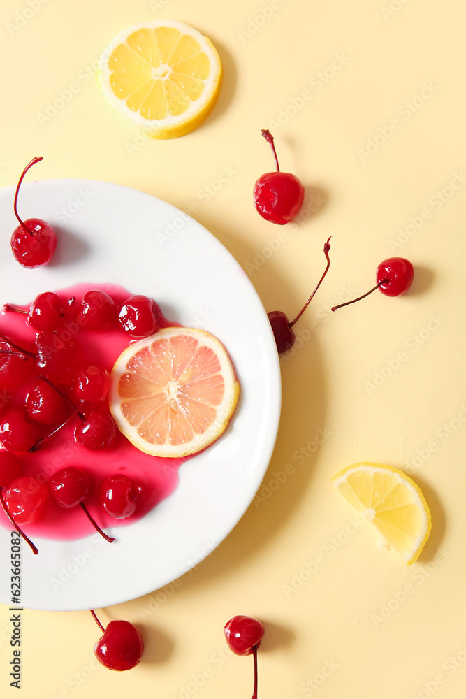 Plate of tasty maraschino cherries and lemon on yellow background