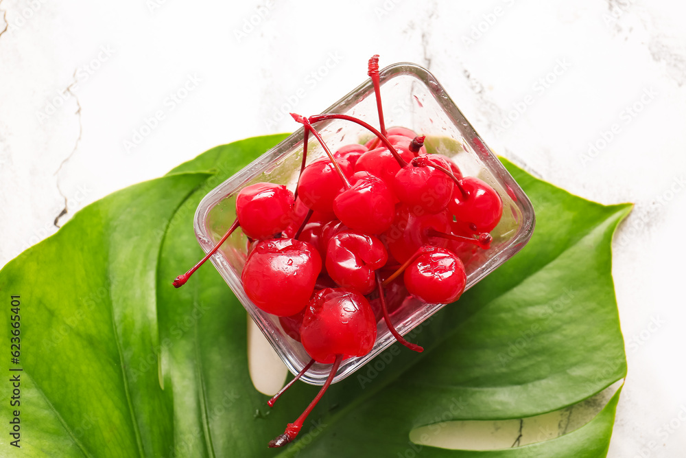 Bowl of tasty maraschino cherries on white marble background