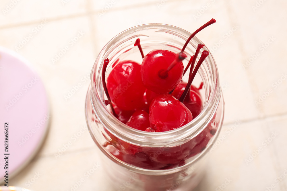 Jar of tasty maraschino cherries on white tile background