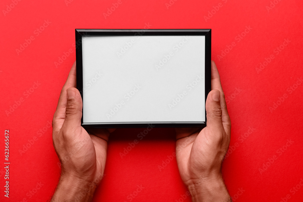 Man holding blank photo frame on red background