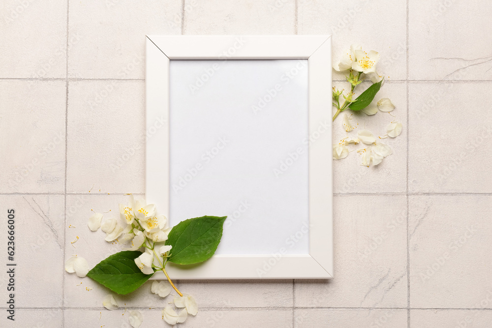 Blank photo frame and beautiful flowers on white tile background