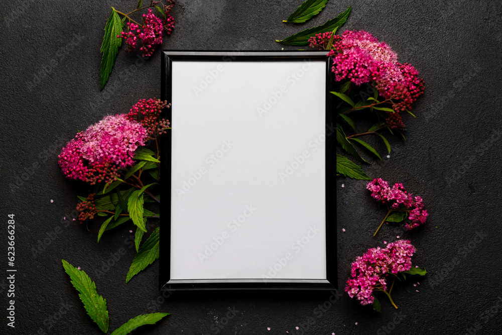 Blank photo frame and beautiful flowers on black background