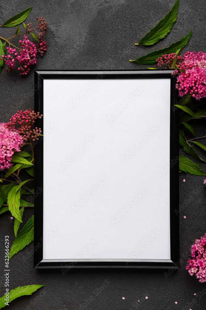 Blank photo frame and beautiful flowers on black background