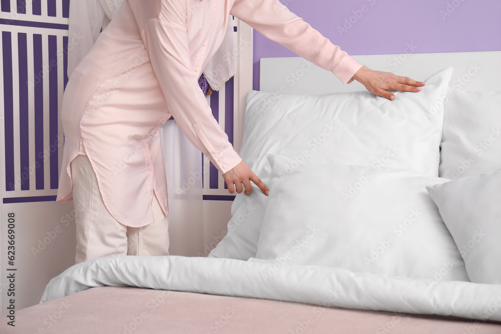 Woman in pajamas making bed at home