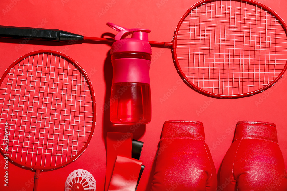 Set of sports equipment with bottle of water on red background, closeup