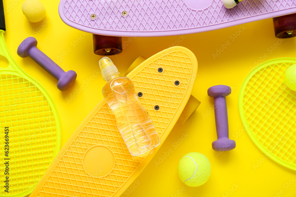 Composition with different sports equipment and bottle of water on yellow background